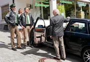 Ein älterer Herr (Hermann Van Ulzen, rechts) steht schimpfend auf dem Parkplatz vor dem Café Rattlinger und erklärt Hubert (Christian Tramitz, 2. von rechts) und Staller (Helmfried von Lüttichau, links), dass jemand in sein Auto gepinkelt hat. Sabrina Rattlinger (Carin C. Tietze, im HG) hört zu.