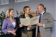 Polizeichef Achtziger (Alexander Duda, r.) und Controllerin Ortmann (Diana Staehly, l.) haben eine Überraschung für Mohr (Max Müller, M).