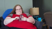 Delana sitting on the couch on her phone