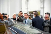 Minister Joachim Schnitzler (Philipp Hochmair, M. mit Komparsen) wird von der Presse belagert.