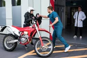 Dr. Marc Lindner (Christian Beermann, r.) trifft auf eine ehemalige Patientin aus der Onkologie. Sanna Wieland (Linda Rohrer, l.) hat sich am Arm verletzt und kommt mit ihrem Motorrad zur Notaufnahme, wo Mikko Rantala (Luan Gummich, M.) ihr zu Hilfe eilt.