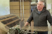 Peter bereitet an der Schärmaschine den nächsten Kettbaum vor. Die Teppichmanufaktur im Allgäu ist eine der wenigen in Deutschland, die alle Produktionsschritte unter einem Dach vereint.