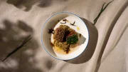 Rosa gebratener Lammrücken mit schwarzem Knoblauch und Auberginencreme.