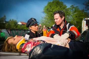 Franzi (Rhea Harder-Vennewald, M.) fragt Dr. Haase (Fabian Harloff) nach dem Zustand des Unfallopfers Nina Hell (Tina Amon Amonsen, l.). Sie muss so schnell wie möglich ins EKH gebracht werden, er vermutet innere Blutungen.