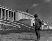 Ein amerikanischer Soldat steht im Zeppelin-Stadion und blickt auf ein Hakenkreuz der Nazis, Nürnberg, Deutschland, 1945. Das Stadion wurde zusammen mit zwei weiteren Stadien von Adolf Hitler für zahlreiche Nazi-Kundgebungen genutzt. Ein amerikanischer Soldat steht im Zeppelin-Stadion und blickt auf ein Hakenkreuz der Nazis, Nürnberg, Deutschland, 1945. Das Stadion wurde zusammen mit zwei weiteren Stadien von Adolf Hitler für zahlreiche Nazi-Kundgebungen genutzt.