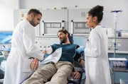 Florian Friedels (Stephan Käfer, M.) gerissene Armarterie wurde gut erstversorgt. Dennoch muss er in den OP. Dr. Matteo Moreau (Mike Adler, l.) und Vivienne Kling (Jane Chirwa, r.) können kaum glauben, dass der eigensinnige Patient sich selbst entlassen will.