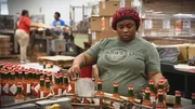 Tabasco bottles on conveyor belt with worker.