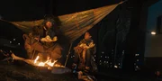 Ama (Amani-Jean Philippe) und ein Griot (Kenneth Herdigein), sitzen am Lagerfeuer, w&auml;rmen sich und essen Fisch. Der Griot erz&auml;hlt Ama Geschichten &uuml;ber Totem-Tiere.