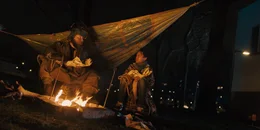 Ama (Amani-Jean Philippe) und ein Griot (Kenneth Herdigein), sitzen am Lagerfeuer, w&auml;rmen sich und essen Fisch. Der Griot erz&auml;hlt Ama Geschichten &uuml;ber Totem-Tiere.