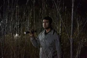 Jason Amos durchsucht den Wald mit einer Taschenlampe.