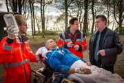 Dr. Haase (Fabian Harloff, 2.v.r.) wundert sich, dass der Jogger, den Hans (Bruno F. Apitz, r.) im Wald gefunden hat, mit dieser Verletzung noch laufen konnte.