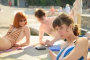 Die Schulclique verbringt ihre Freizeit am Strand. Fanny (Stella Lelouch, r.) ist nicht allzu sehr davon begeistert, dass sich ihr Freund Thomas (Billy Gunnion, M.) zu Vinca (Ivanna Sakhno, l.) hingezogen fühlt.