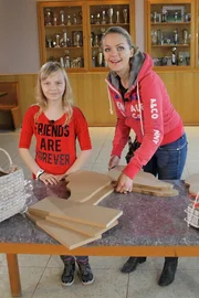 Eva baut mit der kleinen Isabell ein Schmetterlingsregal.