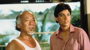 Daniel-san (Ralph Macchio, r.) begleitet Mister Miyagi (Pat Morita, l.) auf eine Reise zur&uuml;ck in seine Heimat Okinawa. Doch ein ungekl&auml;rter Konflikt aus seiner Vergangenheit sucht Mister Miyagi heim.