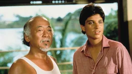 Daniel-san (Ralph Macchio, r.) begleitet Mister Miyagi (Pat Morita, l.) auf eine Reise zur&uuml;ck in seine Heimat Okinawa. Doch ein ungekl&auml;rter Konflikt aus seiner Vergangenheit sucht Mister Miyagi heim.