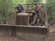 Stan Zuray (L) and Mike McCann (R) standing on the 70-year-old tractor that they think they repaired using household items for parts. The two men are ready to test out their hard work. If the tractor runs they can finally begin their silver mining venture.