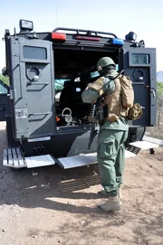 Nogales, Arizona, USA: A customs and border protection agent loads up his weapons and gear by an armored vehicle.
