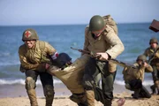 Kampfsanitäter Waverly Woodson Jr. (gespielt von Francesco Di Rauso) hilft, Verwundete in Sicherheit zu bringen, in einer Szene einer historischen Nachstellung des Zweiten Weltkriegs für "Erased: WW2's Heroes of Color". Waverly Woodson Jr. war ein Kampfsanitäter, der mit dem 320th Barrage Balloon Battalion am D-Day diente. (National Geographic/Rekha Garton)