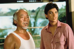 Daniel-san (Ralph Macchio, r.) begleitet Mister Miyagi (Pat Morita, l.) auf eine Reise zur&uuml;ck in seine Heimat Okinawa. Doch ein ungekl&auml;rter Konflikt aus seiner Vergangenheit sucht Mister Miyagi heim.