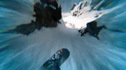 Travis Rice aus der Vogelperspektive mit Spezialeffekten, als er sich darauf vorbereitet, sich mit seinem Snowboard auf einem Berg in Alaska durch zwei Felsen zu quetschen. (Bildnachweis: Travis Rice, Inc)