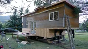 Phil and Shane have built the deck in the front of the tiny house and are working on the metal siding, for Fisher tiny house build, in Swan Valley, Idaho, as seen on Tiny House, Big Living.