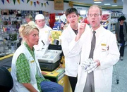 Schumann (Lutz Herkenrath, r.) ist vor Frau Stöhr von der Konzernzentrale auf der Flucht, da sie ihm angeblich an die Wäsche will. Er versteckt sich bei Kevin (Kevin Lorenz, 2.v.l.), Bernie (Georg Alfred Wittner) und Rita (Gaby Köster) an der Kasse.