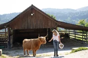 Christine Baumann bei ihren Schottischen Hochlandrindern. Die Tiere leben ganzjährig draußen und haben einige Unterstände rund um den Hof.