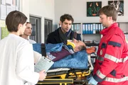 Heinz Lorbert wird in die Notaufnahme eingeliefert, nachdem er von einem Auto angefahren wurde. V.l.n.r. Dr. Theresa Koshka (Katharina Nesytowa), Julia Berger (Mirka Pigulla), Dr. Niklas Ahrend (Roy Peter Link), Heinz Lorbert (J&uuml;rgen Haug), Komparse.