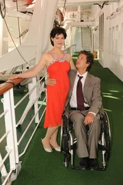 An der Reling steht Caro Setzer (Esther Zimmering) neben Roland Wagner (Kristian Kiehling), der im Rollstuhl sitzt. An der Reling steht Caro Setzer (Esther Zimmering) neben Roland Wagner (Kristian Kiehling), der im Rollstuhl sitzt.