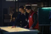 A Nepalese investigator (played by Leon Aureus) and Andrew Robinson (played by Philip Graeme) inspect a topographical map to help determine the cause of Pakistan International Airlines Flight 268's tragic accident.