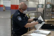 Ein Kameramann filmt den CBP-Beamten Cisneros beim Öffnen eines gekennzeichneten Pakets auf der Suche nach versteckter Schmuggelware in der Poststelle des JFK International Airport in New York (National Geographic).