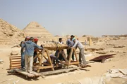 Saqqara war über 3000 Jahre lang ein Friedhof. Das Herzstück der Ausgrabungsstätte des Teams ist ein 100 Fuß tiefer Schacht, bekannt als K24, der jetzt mit einer manuellen Winde ausgestattet ist. Seine Lage ist ein "erstklassiges Grundstück" für eine heilige Mumifizierungsstätte, denn die große Stufenpyramide von Saqqara wacht über die Gräber und Schächte. (National Geographic/Piers Leigh) Saqqara war über 3000 Jahre lang ein Friedhof. Das Herzstück der Ausgrabungsstätte des Teams ist ein 100 Fuß tiefer Schacht, bekannt als K24, der jetzt mit einer manuellen Winde ausgestattet ist. Seine Lage ist ein "erstklassiges Grundstück" für eine heilige Mumifizierungsstätte, denn die große Stufenpyramide von Saqqara wacht über die Gräber und Schächte. (National Geographic/Piers Leigh)
