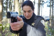 Officer Hazel zielt mit ihrer Waffe in den Wald.