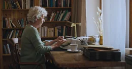 Claretta (Carla Becker) schreibt auf ihrer Schreibmaschine.
