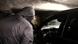 Ein vermummter Mann &ouml;ffnet die Fahrert&uuml;r eines Autos in einer Tiefgarage.