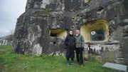 Sam Willis und Robert Joe stehen vor einem Geschütz-Kasemattenbau von Belgiens Fort Eben Emael; historische Aufnahme und Beschreibung des Forts.