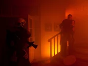 Pia Heilmann (Hendrikje Fitz, rechts) sucht in den Flammen verzweifelt nach ihrem Sohn. Roland Heilmann (Thomas Rühmann) und die Feuerwehrleute versuchen, sie davon abzuhalten. Die Flammen breiten sich immer schneller aus.