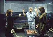 In der Tiegarage weist Burt (Burt Reynolds, M.) die FBI-Agenten, Scully (Gillian Anderson, l.) und Monica (Annabeth Gish, l.), darauf hin, dass sie vielleicht selbst die nächsten Opfer des Serienmörders sein könnten.