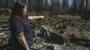 Anastasia zeigt auf das, was von ihrem Haus nach dem Waldbrand &uuml;brig geblieben ist.