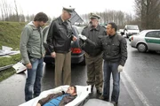 Ben (Tom Beck, l.) und Semir (Erdogan Atalay, r.) haben in dem Unfallwagen Kokain gefunden. F&uuml;r Streifenpolizist Bonrath (Gottfried Vollmer, 2.v.l.) ist der Tote kein Unbekannter: Es handelt sich um Rick Faber (Nils Adolf Schulz, lieg.), den Gesch&auml;ftspartner seines Sohnes. Kollege Herzberger (Dietmar Huhn) ist best&uuml;rzt.