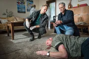 Moritz Brenner (Johannes Hendrik Langer, l.) und Jan Maybach (Marco Girnth, r.) untersuchen den Tatort, an dem das Opfer Juri Kabowski (Volker Wackermann, M.) auf dem Boden liegt.