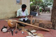 Man sitting, hollowing out wood for sitar, carving openings. Man sitting, hollowing out wood for sitar, carving openings.
