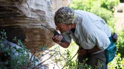 Eric Drummond looks into the cave, talking into his walkie talkie.