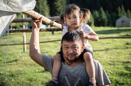 Vater Mirlan tr&auml;gt seine Tochter auf den Schultern.