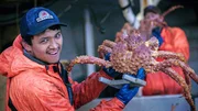 Ein Mitglied der "Wizard"-Crew hält eine große Krabbe.