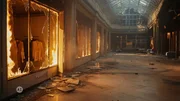 Ein verlassenes Einkaufszentrum mit sichtbaren Schäden. Zerbrochene Glasscheiben, Trümmer auf dem Boden und ausgebrannte Schaufenster prägen die Szene. Einige Geschäfte zeigen Flammen im Inneren. Ein verlassenes Einkaufszentrum mit sichtbaren Schäden. Zerbrochene Glasscheiben, Trümmer auf dem Boden und ausgebrannte Schaufenster prägen die Szene. Einige Geschäfte zeigen Flammen im Inneren.