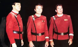 Die Enterprise ist mit Captain Kirk (William Shatner, r.), Dr. McCoy (DeForest Kelley, M.), Mr. Spock (Leonard Nimoy, l.) und der gesamten Mannschaft von dem vulkanischen Herrscher Sybok gekapert worden. Er will mit dem Raumschiff einen Planeten anfliegen, auf dem Gott wohnen soll...