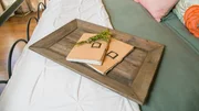 A close up of the wooden tray and journals on the bed in the master bedroom of the newly renovated Childers home, as seen on Fixer Upper. (after)