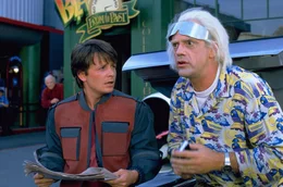 Doc Brown (Christopher Lloyd, r.) und Marty (Michael J. Fox) reisen ins Jahr 2015, um Martys zuk&uuml;nftiger Familie zu helfen. Doch bei ihrem Ausflug in die Zukunft wird ihre Zeitmaschine gestohlen, was verheerende Auswirkungen auf die Gegenwart hat.