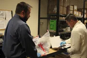 HSI Agent Steve Ledgerwood and Mario Cebrera place the gun and drugs that were seized in the evidence room.